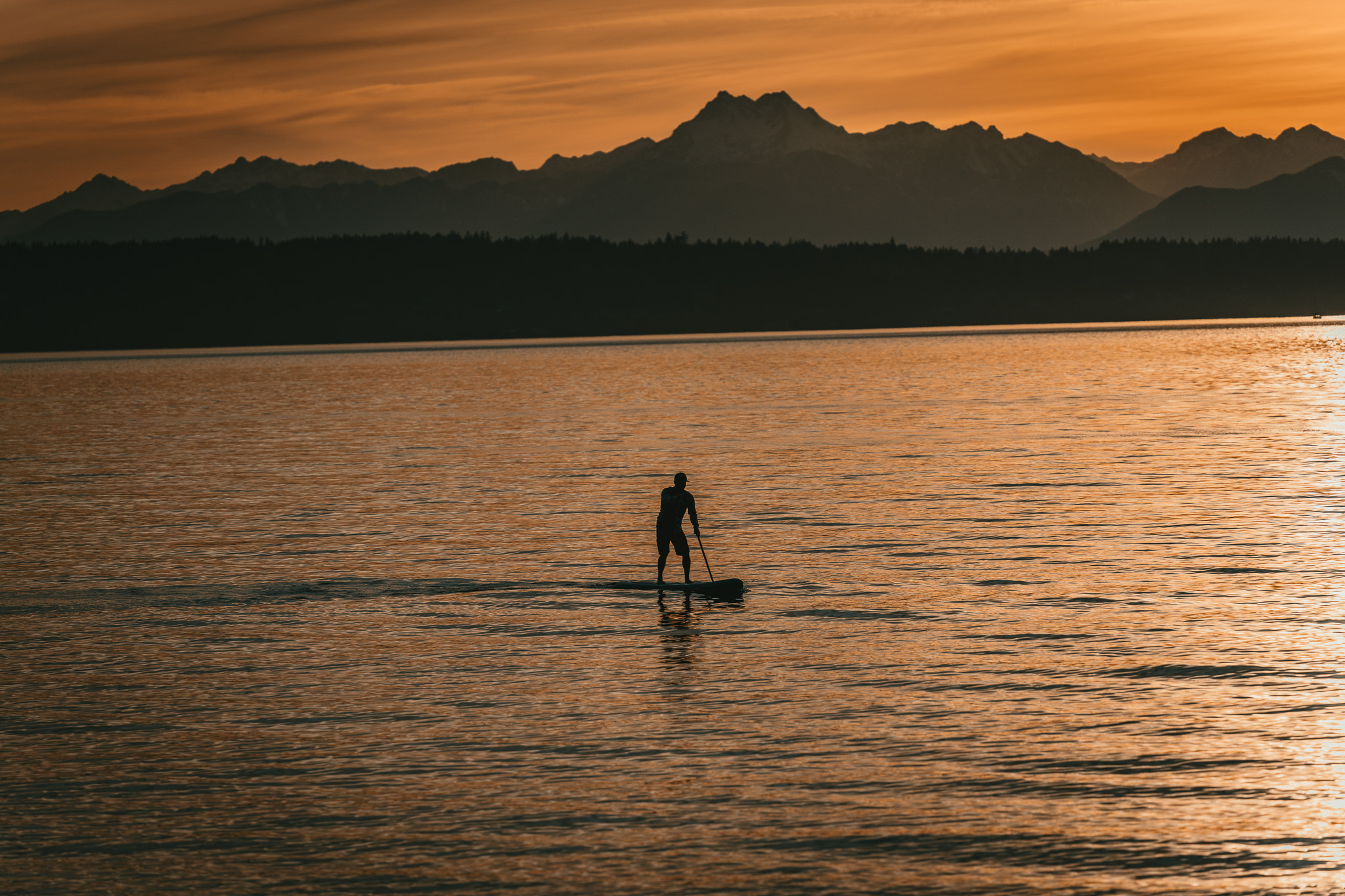 Paddleboarder at sunset on mountain lake