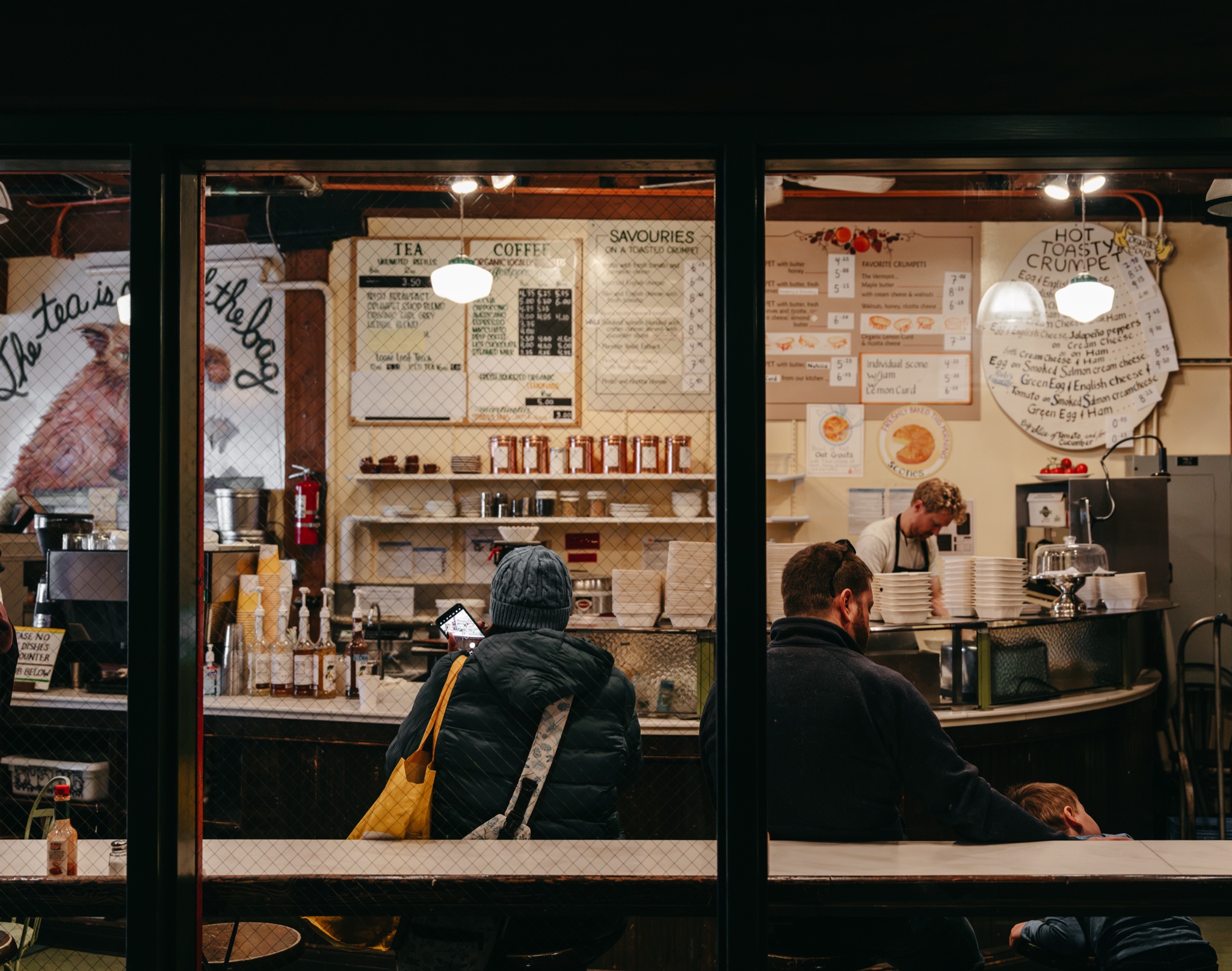 Diners at the Crumpet Shop counter seen through the window grid, Pike Place Market